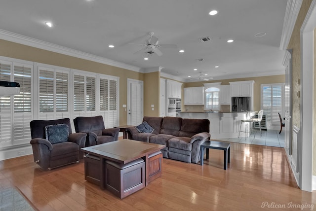 living room with ceiling fan, light wood-type flooring, and crown molding