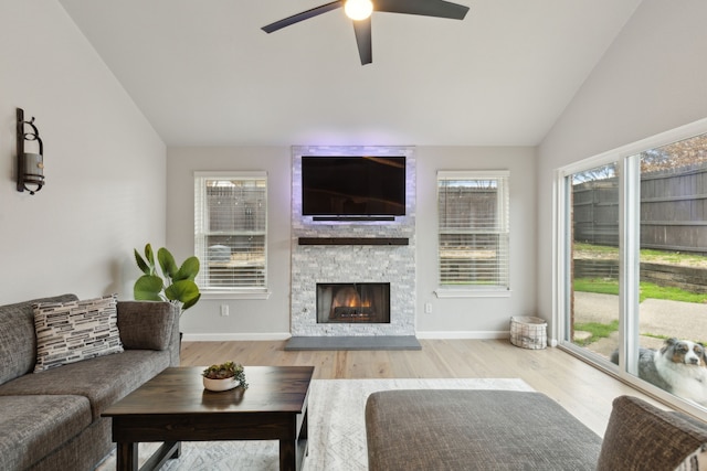 living room featuring baseboards, ceiling fan, wood finished floors, vaulted ceiling, and a fireplace