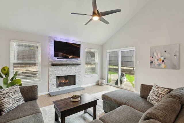 living room featuring light wood-type flooring, high vaulted ceiling, ceiling fan, and a fireplace