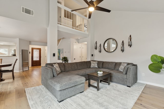 living room featuring ceiling fan, a towering ceiling, and hardwood / wood-style floors