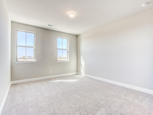 unfurnished room featuring visible vents, light carpet, and baseboards