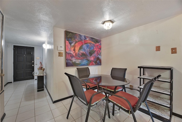 dining space featuring light tile patterned flooring, a textured ceiling, and baseboards