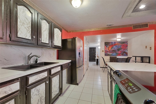 kitchen featuring stainless steel appliances, a sink, visible vents, light countertops, and dark brown cabinets