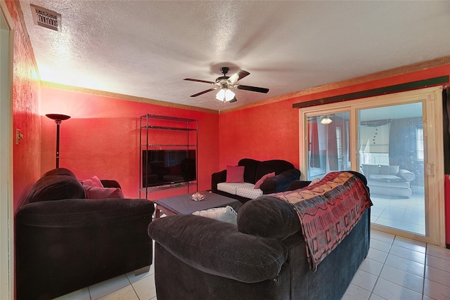 living room featuring light tile patterned floors, visible vents, a textured wall, ceiling fan, and a textured ceiling