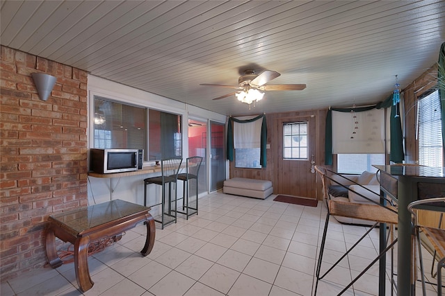 interior space featuring wooden ceiling, brick wall, ceiling fan, and light tile patterned flooring