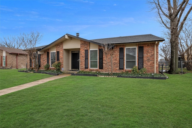 view of front facade with brick siding, a front yard, fence, and a shingled roof