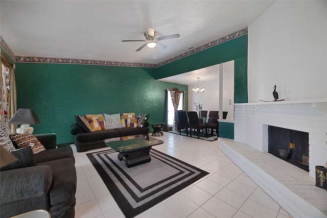 living area featuring a brick fireplace, light tile patterned flooring, and ceiling fan with notable chandelier