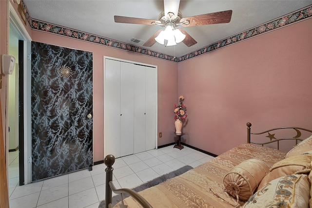 bedroom with light tile patterned floors, a closet, visible vents, ceiling fan, and a textured ceiling