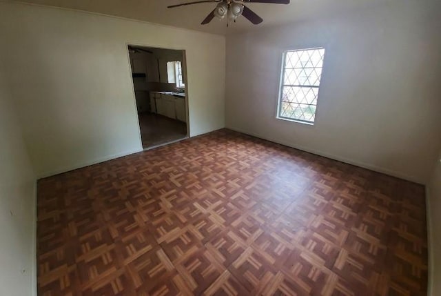 unfurnished room featuring ceiling fan and dark parquet flooring