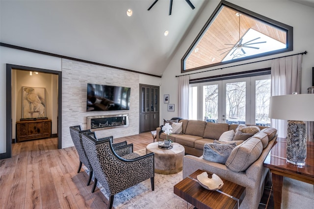 living room with hardwood / wood-style flooring, french doors, ceiling fan, a large fireplace, and high vaulted ceiling