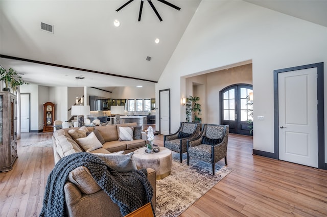 living room with high vaulted ceiling, light hardwood / wood-style floors, and french doors