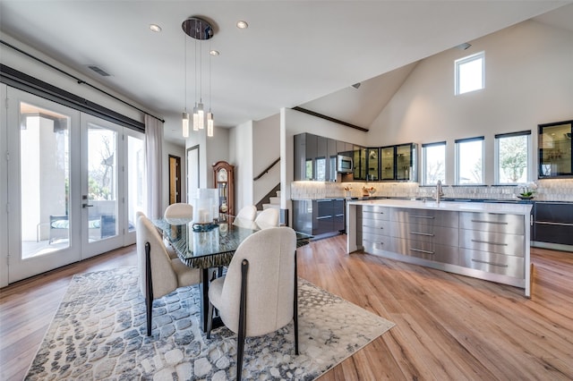 dining area featuring high vaulted ceiling, light hardwood / wood-style floors, and french doors