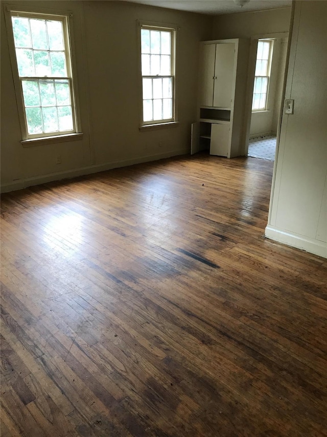 empty room with dark wood-type flooring and a wealth of natural light