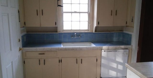 kitchen featuring decorative backsplash, sink, and dishwashing machine