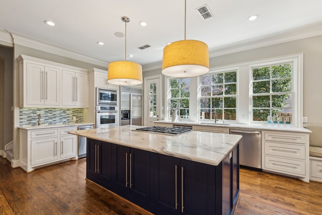 kitchen with built in appliances, pendant lighting, white cabinetry, and a center island