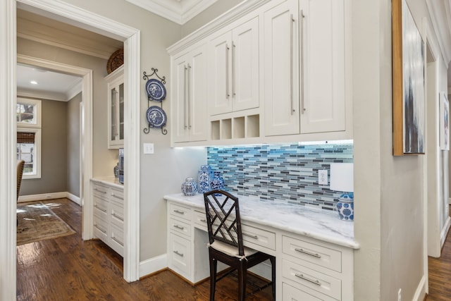 office space with crown molding, built in desk, and dark hardwood / wood-style floors