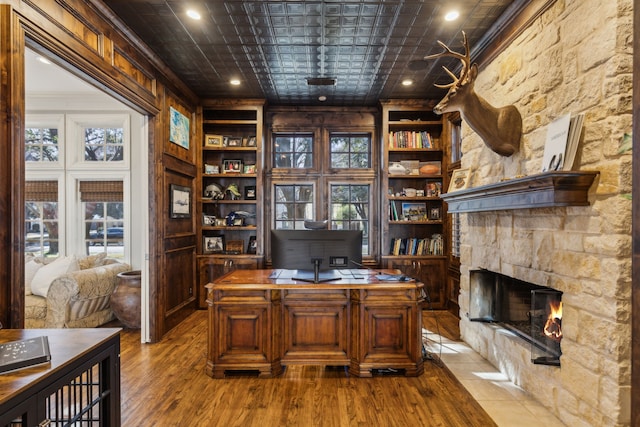 office with light wood-type flooring, plenty of natural light, built in shelves, and a fireplace