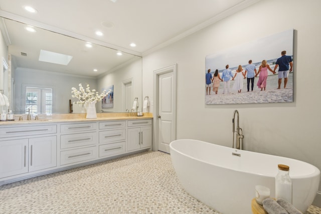 bathroom featuring crown molding, a skylight, a bathtub, and vanity