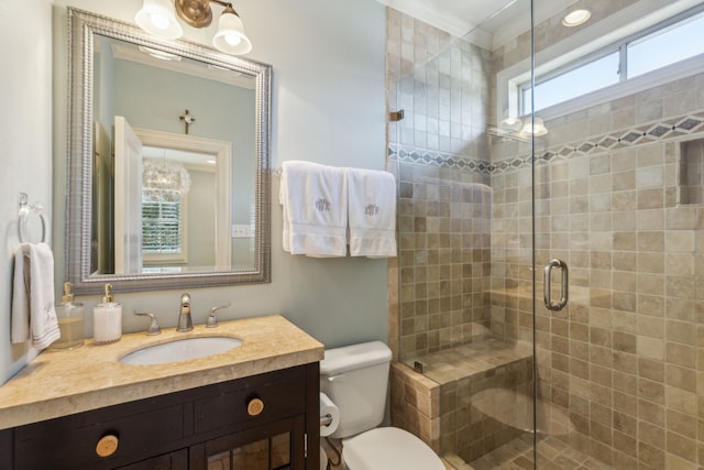 bathroom with toilet, crown molding, vanity, and a shower with door