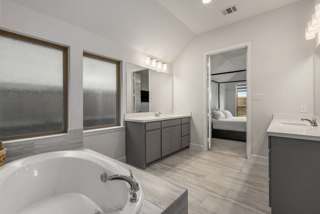 5716 Turner May Dr, Fort Worth, TX 76126 - ensuite bathroom featuring two vanities, vaulted ceiling, a jetted tub, and baseboards