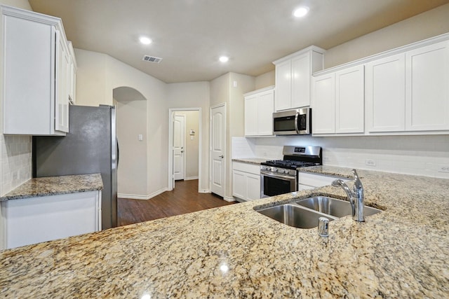 kitchen featuring white cabinets, stainless steel appliances, light stone counters, and sink