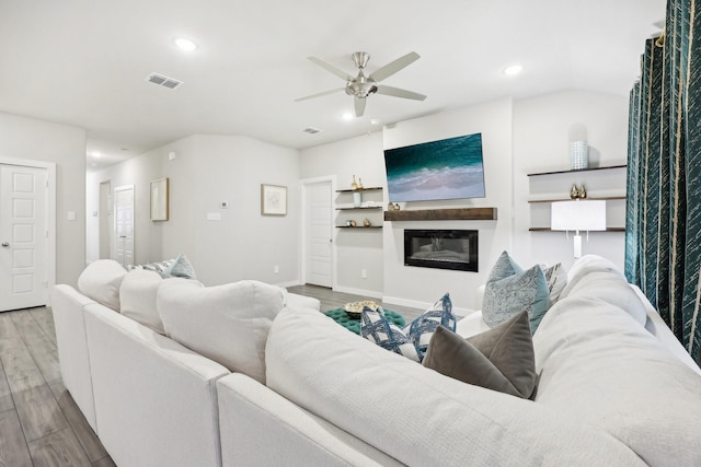 living room with light hardwood / wood-style floors, vaulted ceiling, and ceiling fan