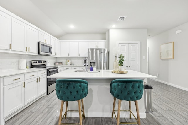 kitchen with white cabinets, appliances with stainless steel finishes, and a center island with sink