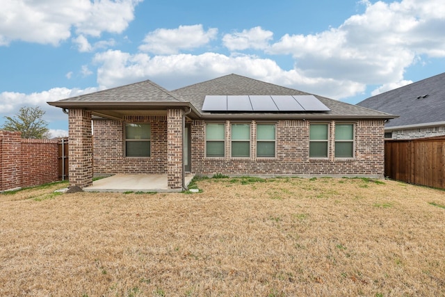 rear view of property featuring a patio, solar panels, and a yard