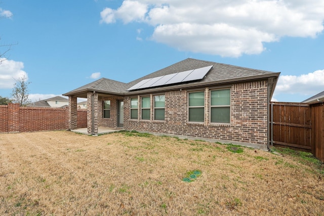 rear view of house featuring a patio, solar panels, and a yard