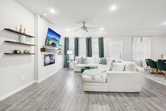 living room featuring ceiling fan, light wood-type flooring, and a healthy amount of sunlight