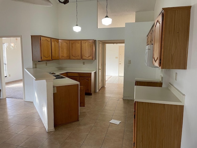 kitchen with light tile patterned floors, sink, hanging light fixtures, and a towering ceiling