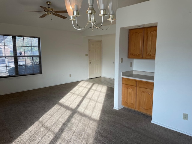 unfurnished dining area with ceiling fan with notable chandelier and light carpet