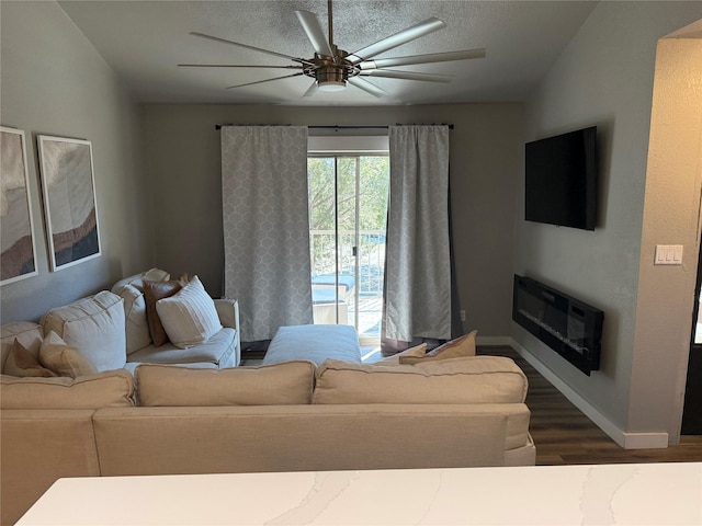 living room with dark hardwood / wood-style flooring, ceiling fan, and a textured ceiling