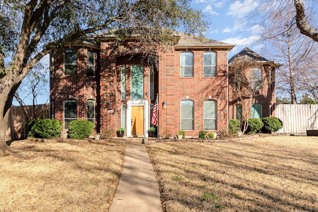 view of front of property with a front yard, fence, and brick siding