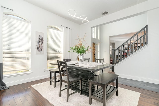 dining room featuring stairs, wood finished floors, visible vents, and baseboards