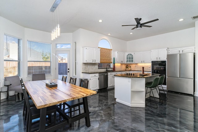 kitchen featuring white cabinets, dark countertops, appliances with stainless steel finishes, backsplash, and a sink