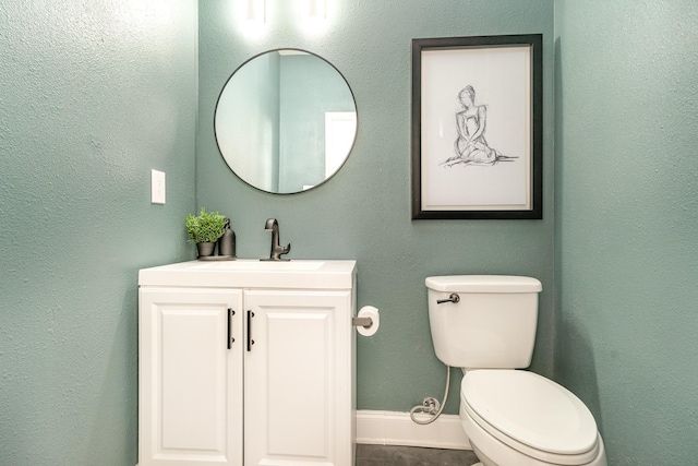 bathroom featuring baseboards, vanity, and toilet