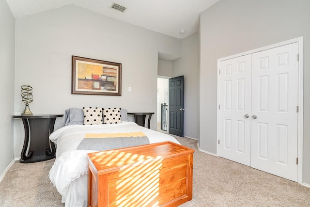 carpeted bedroom with lofted ceiling, a closet, visible vents, and baseboards