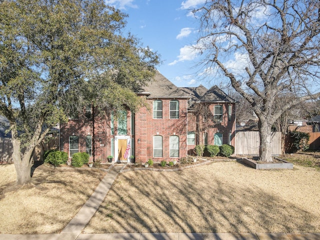 view of front of home featuring brick siding, a front lawn, and fence