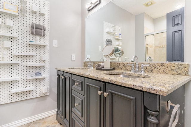 full bathroom with a tile shower, double vanity, tile patterned flooring, and a sink