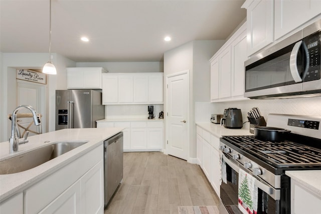 kitchen featuring appliances with stainless steel finishes, sink, hanging light fixtures, and white cabinetry