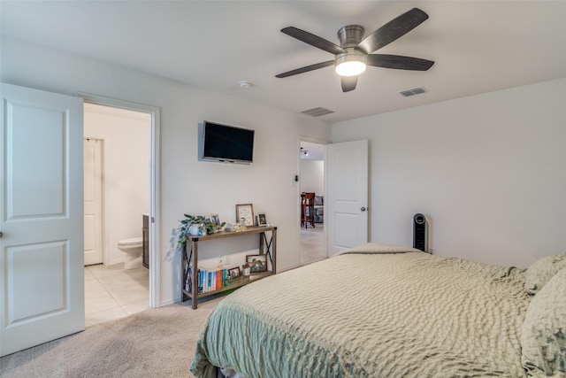 bedroom featuring a ceiling fan, ensuite bath, visible vents, and light colored carpet