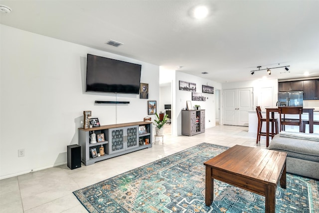 living room featuring light tile patterned floors, baseboards, visible vents, and track lighting