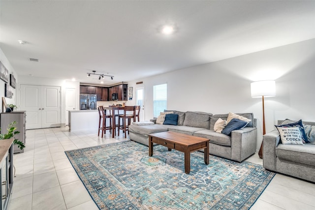 living room featuring light tile patterned flooring, visible vents, and track lighting