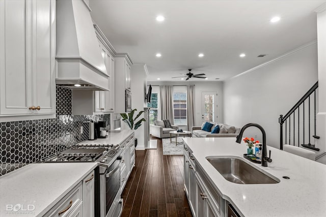 kitchen with light stone counters, stainless steel range with gas cooktop, sink, custom exhaust hood, and dark hardwood / wood-style floors