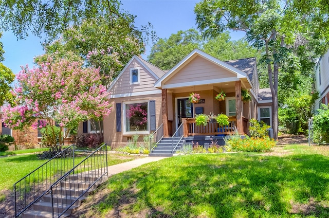 bungalow-style home featuring covered porch and a front yard