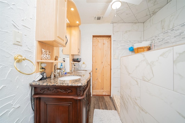 bathroom with hardwood / wood-style flooring, ceiling fan, vanity, and a textured ceiling