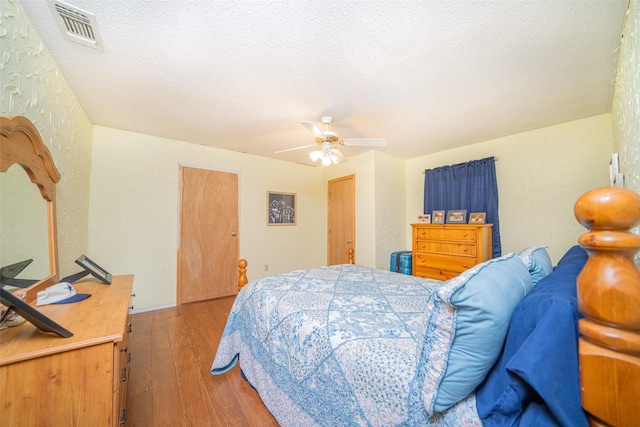 bedroom with ceiling fan, a textured ceiling, and hardwood / wood-style floors