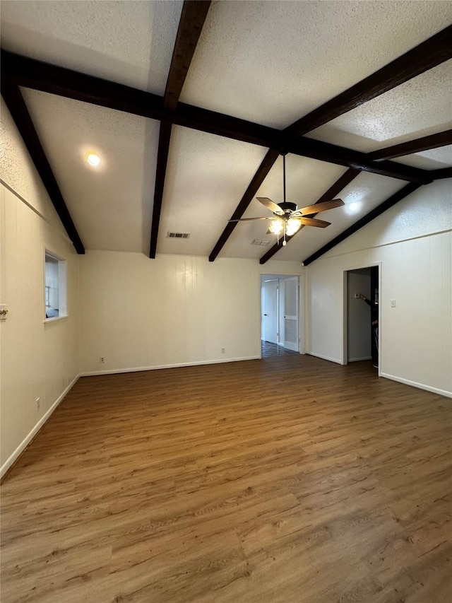 spare room featuring hardwood / wood-style floors, lofted ceiling with beams, and a textured ceiling