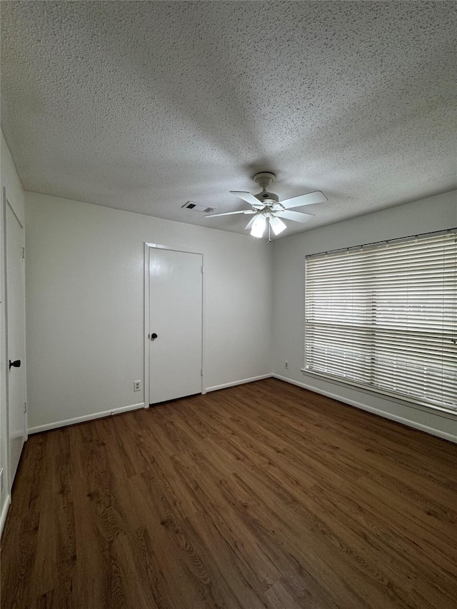 spare room featuring ceiling fan, a textured ceiling, and dark hardwood / wood-style flooring